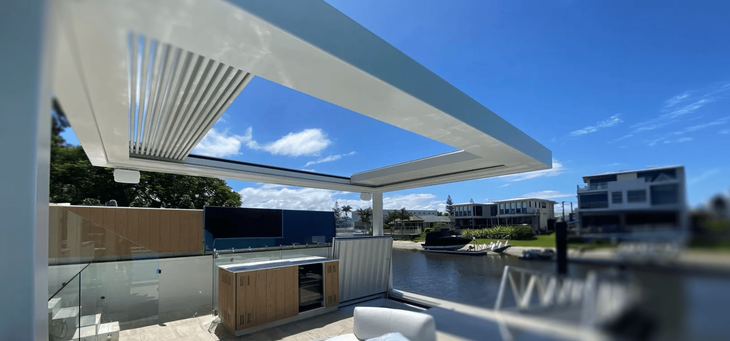 Outdoor living area with Louvretec opening roof, seating, and waterfront view.
