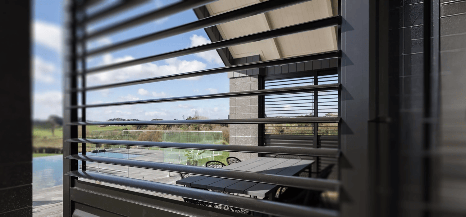 Balcony side view showing a rectangular sun louvre privacy screen, with a pool visible through the slats.
