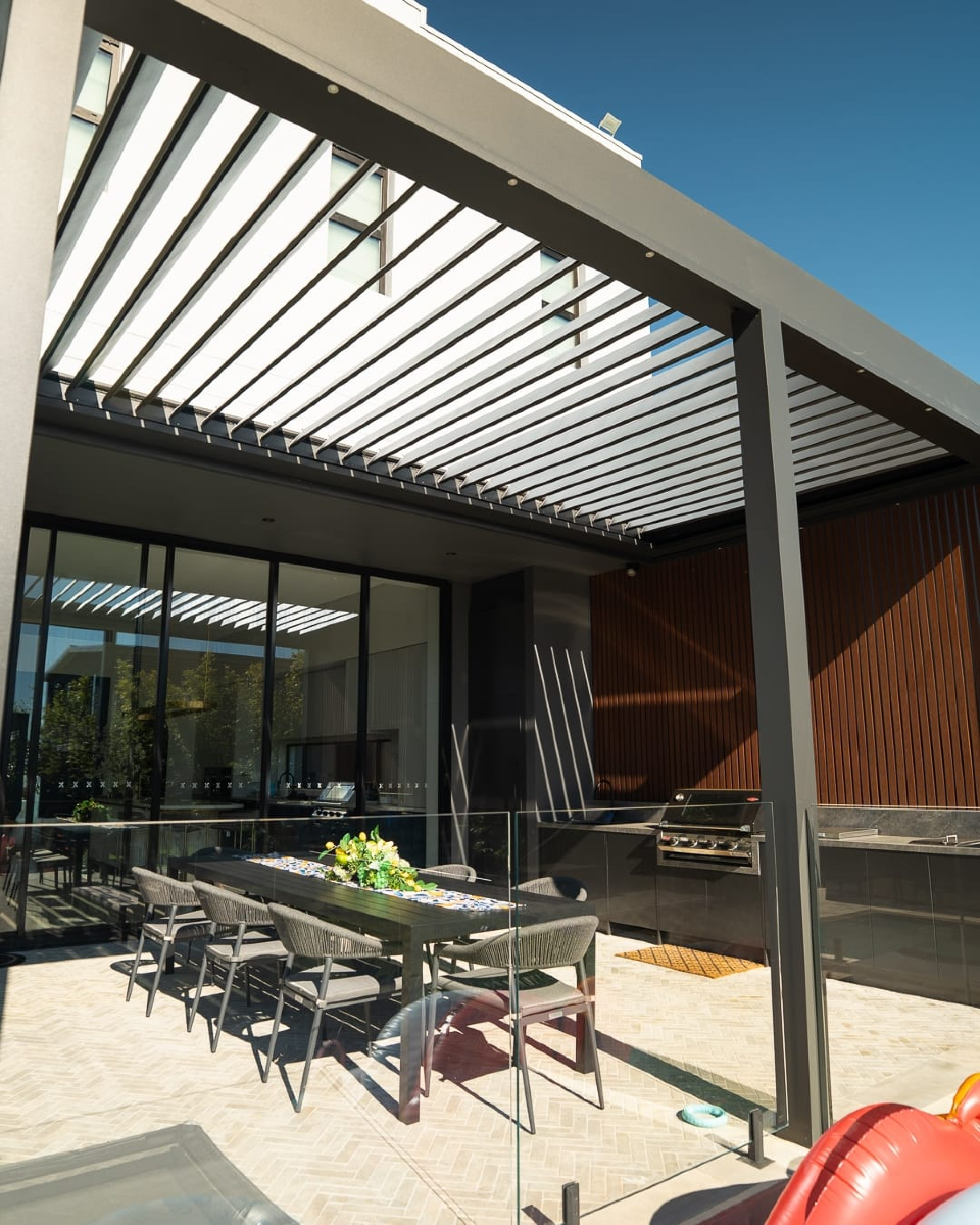 Modern Australian home with a motorised opening louvre roof over an outdoor entertaining area.